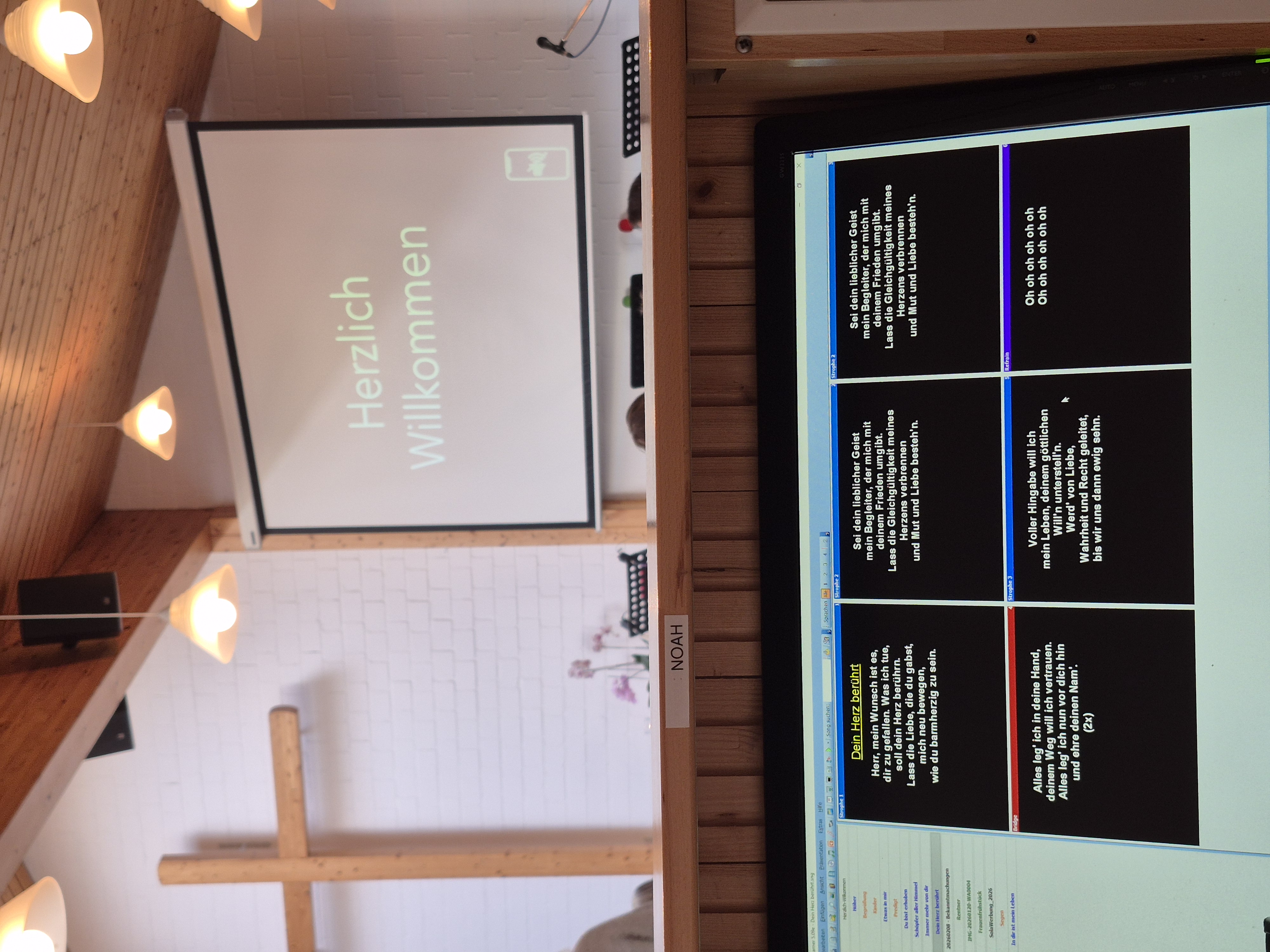 Ansicht hinter den Kulissen der Technik eines Gottesdienstes. Im Hintergrund sieht man Kreuz und die Beamerleinwand