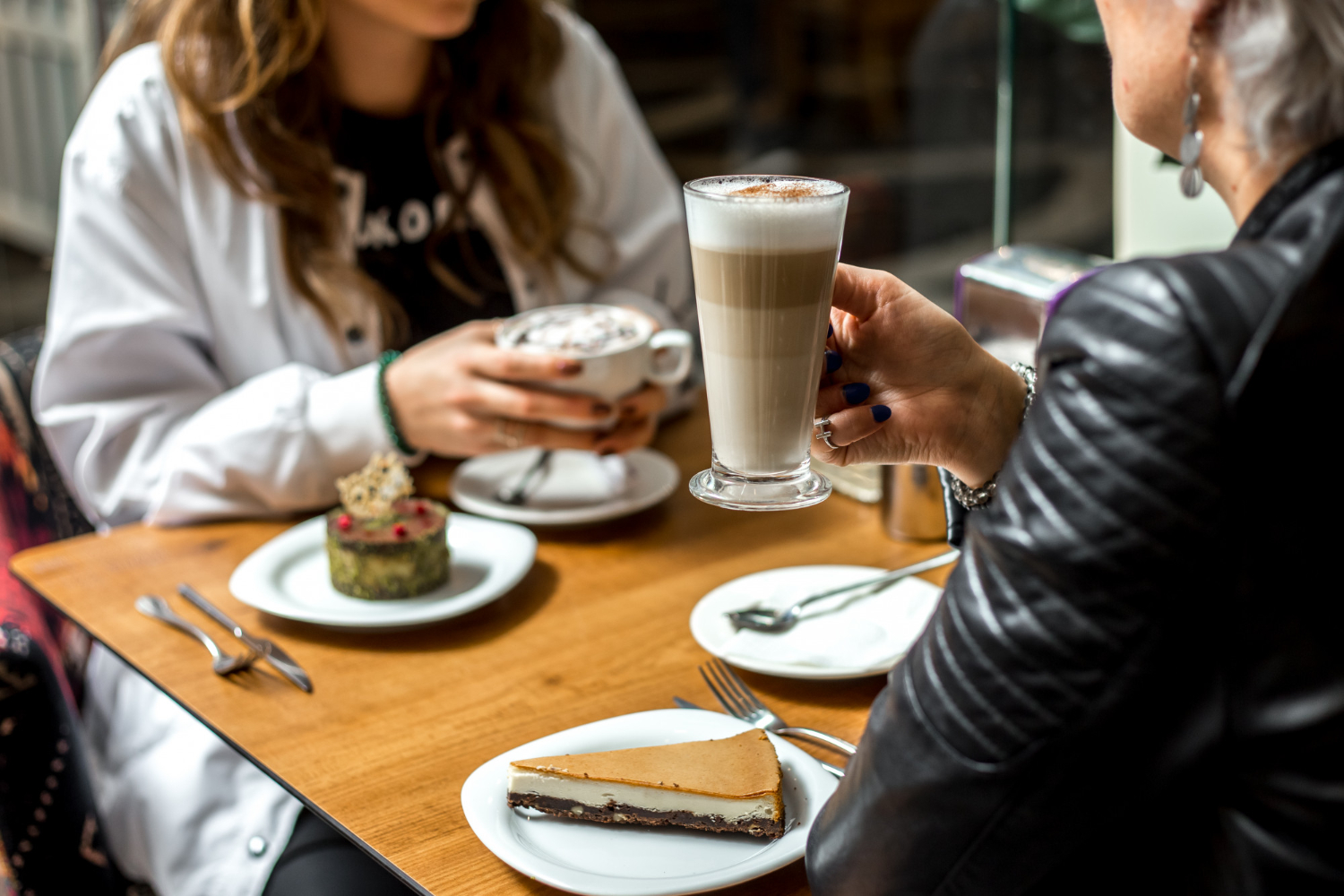 Zwei Frauen genießen ein Kaffeegetränke und Kuchen an einem kleinen Tisch