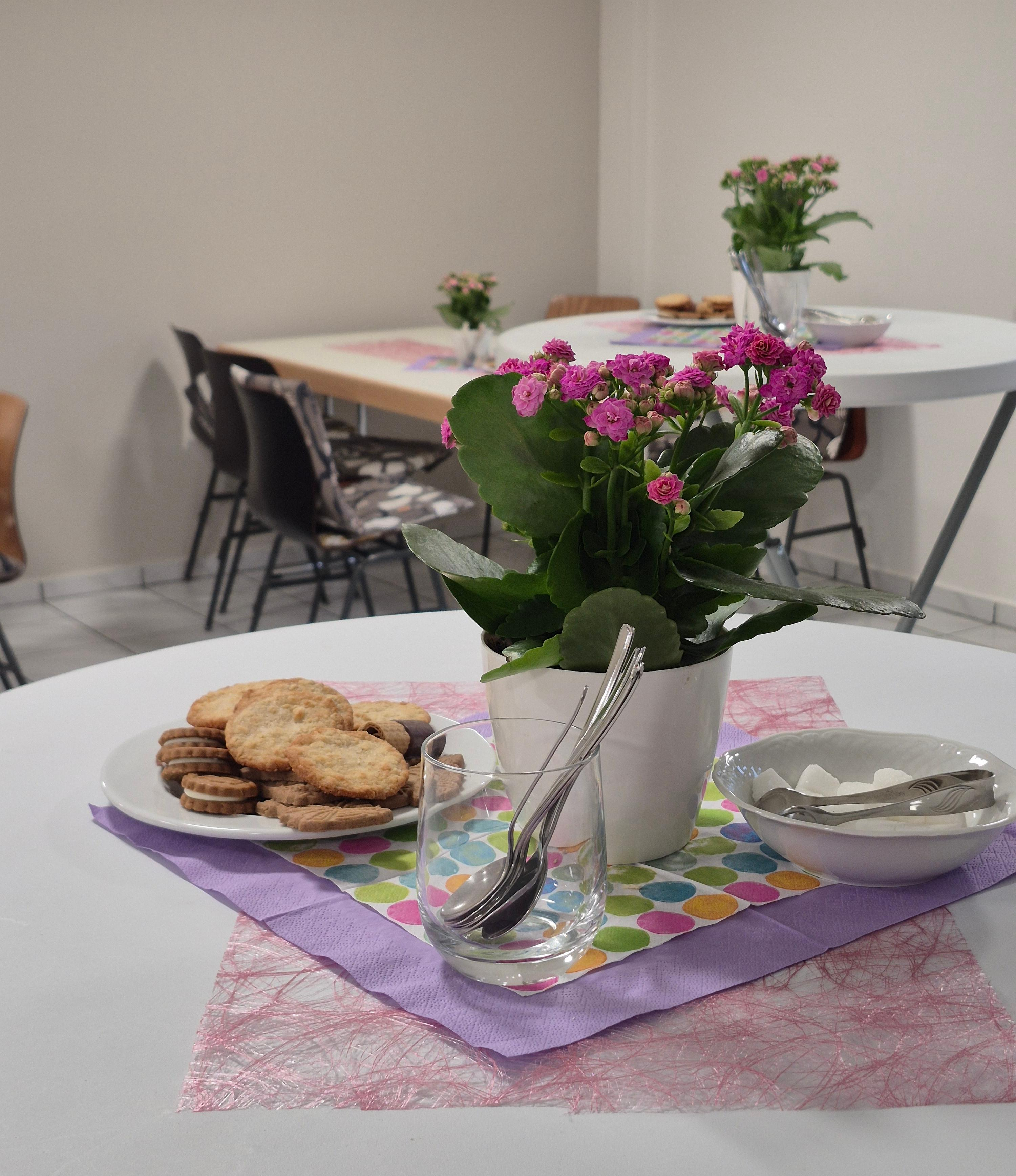 Foto von einem Stehtisch im Gemeindecafé. Darauf liegen Kekse, eine pinke Blume und Zucker und Kaffeelöffel.
